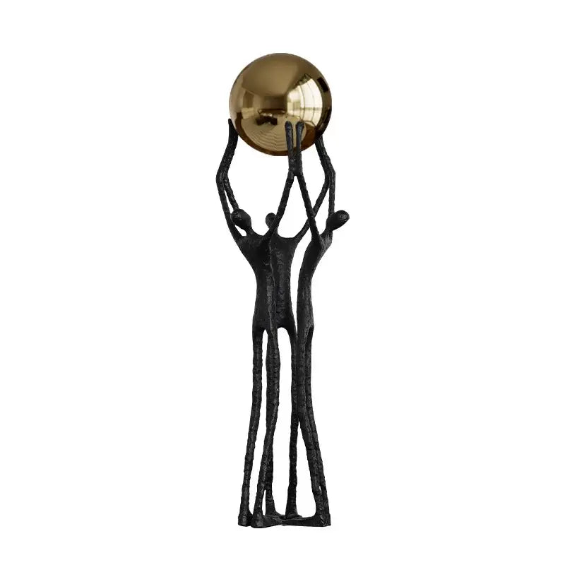 Abstract black cast iron sculpture of three figures supporting a polished golden ball holder for living room decor