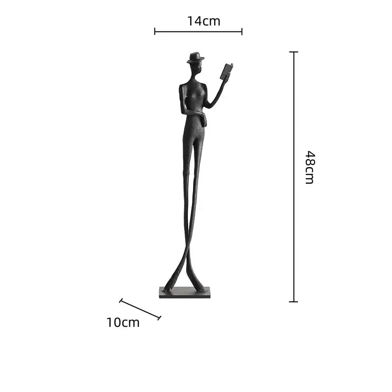 A sleek black metal decorbites human figure sculpture wearing a hat and holding a book for living room decor