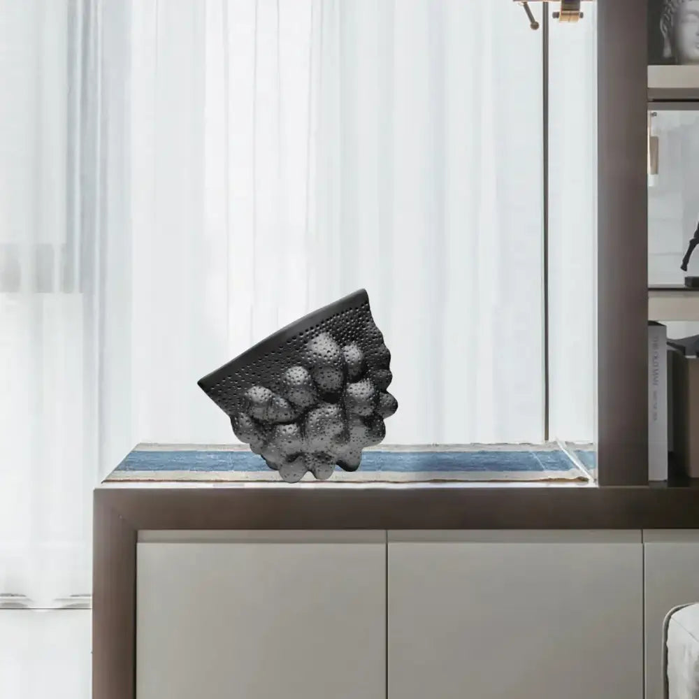 Abstract black ceramic pleated vase with textured perforated surface and rounded protrusions for decorbites black ceramic decor