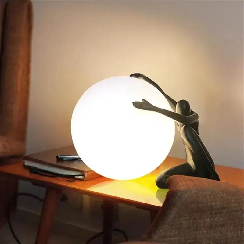 A sleek white spherical lamp with a black abstract ball holding character resin figurine for living room decor