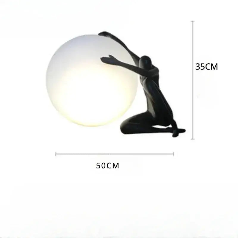 Abstract black and red ball holding character resins lamp with a kneeling figure holding a glowing spherical globe for living room