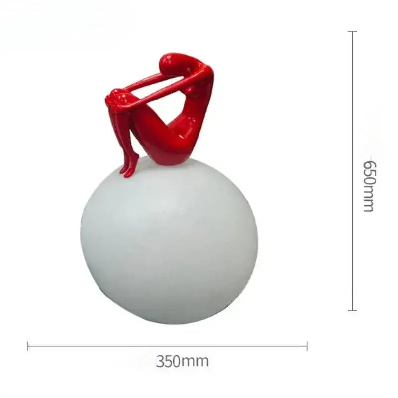 A glossy red ball holding character resin sculpture on a matte white spherical base for living room decor