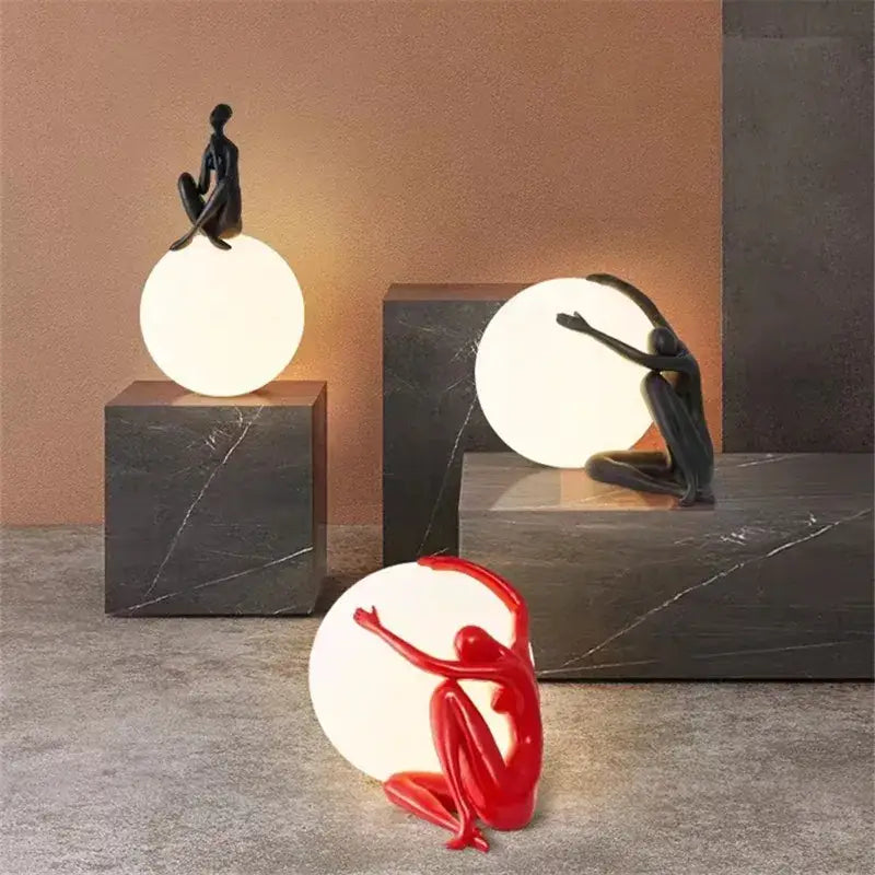 Abstract black and red ball holding character resins lamp featuring human figurine sculptures on glowing spherical lamps