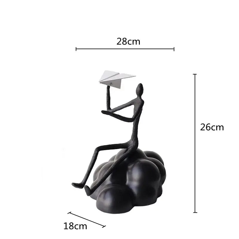 Abstract black resin paper airplane cloud figurine featuring a matte seated human holding a white paper airplane for decor