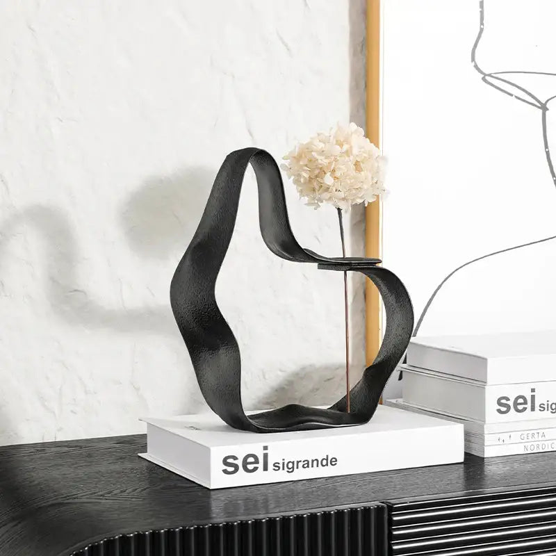 Abstract black resin ring sculpture with flowing curves holding dried white hydrangea for home decor decorbites geometric