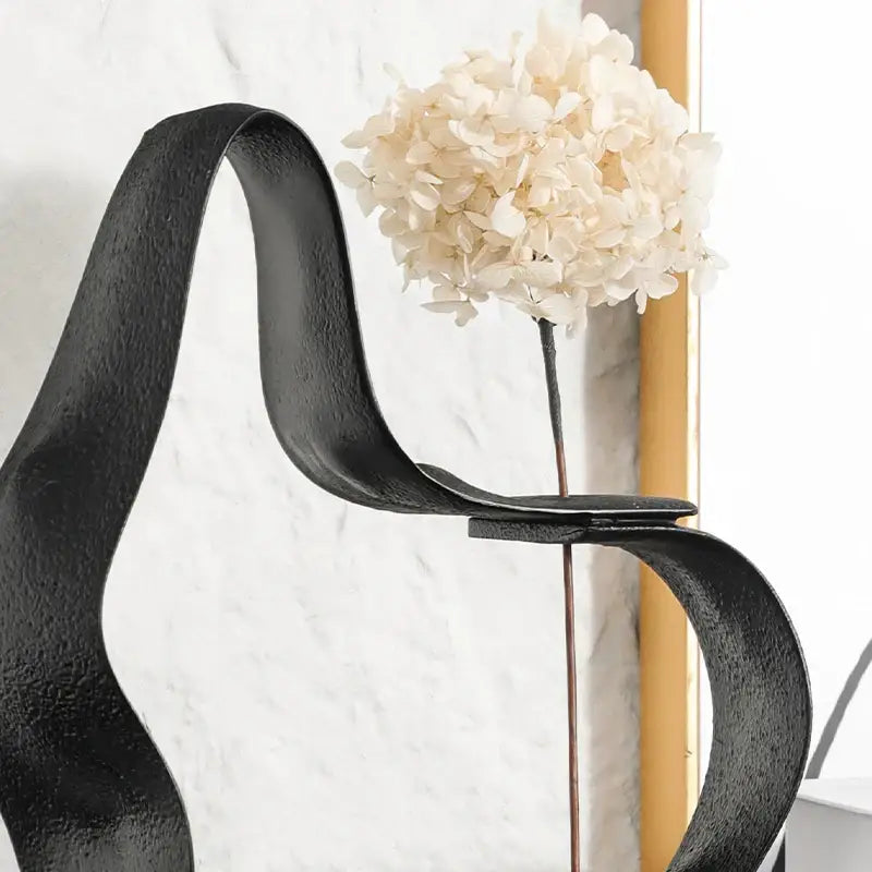 Abstract black resin ring sculpture with a black wrought iron design holding a cream hydrangea bloom for home decor decorbites geometric