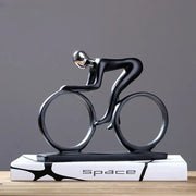 Abstract black and silver resin cyclist statue with minimalist design on white base featuring space lettering for decorbites decor