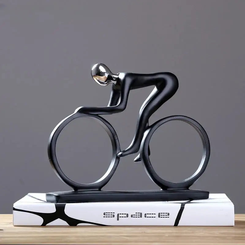 Abstract black and silver resin cyclist statue with minimalist design on white base featuring space lettering for decorbites decor
