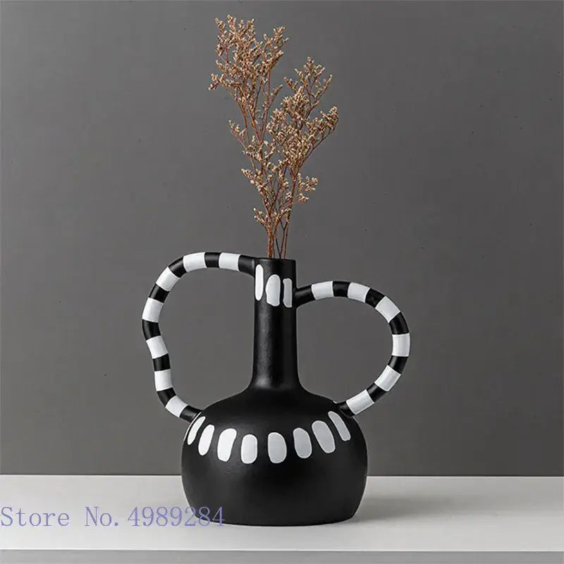 Abstract black and white ceramic vase with white spots and striped handles holding dried golden branches decorbites ceramic vase