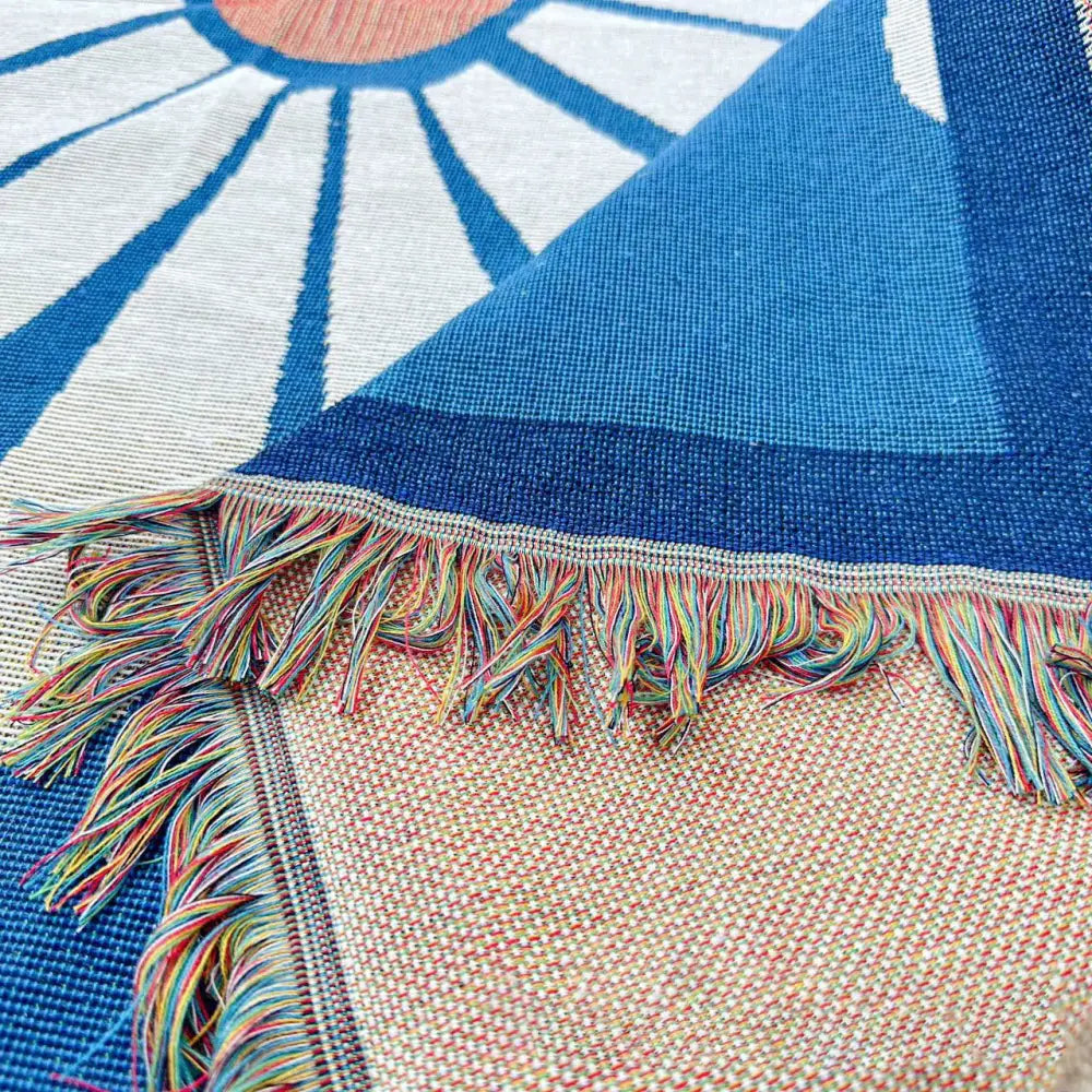 Abstract blue and beige geometric knitted tassels throw blanket with blue and white sun design and multicolored fringe edge