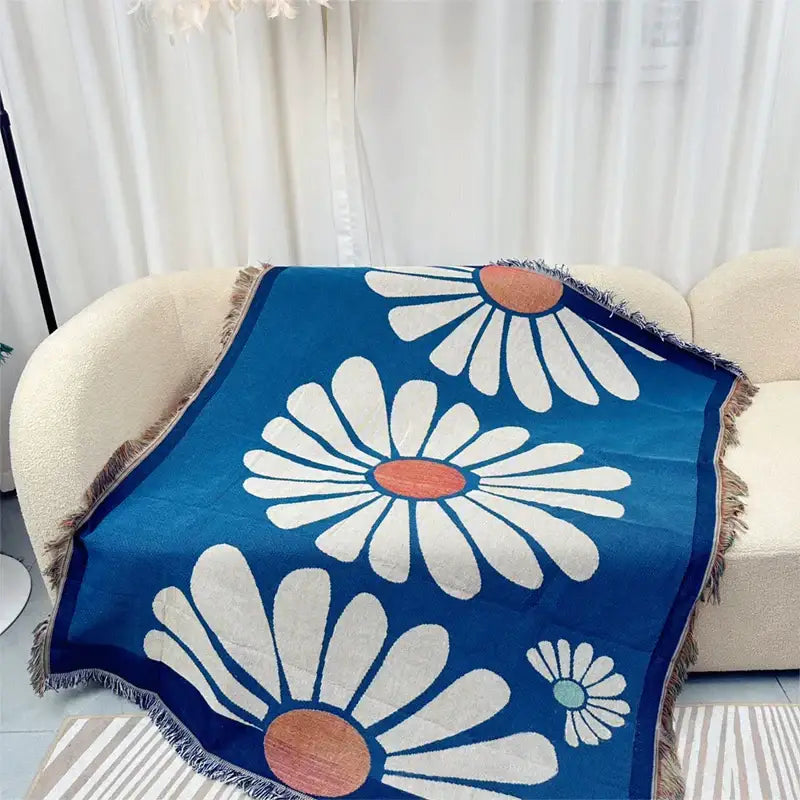 Blue throw blanket with white daisies and fringed edges featuring geometric knitted tassels for bedroom decor