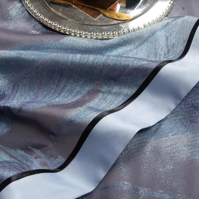 A shimmering blue satin table runner with black trim complements the abstract blue and gray 1500tc jacquard egyptian cotton bedding set