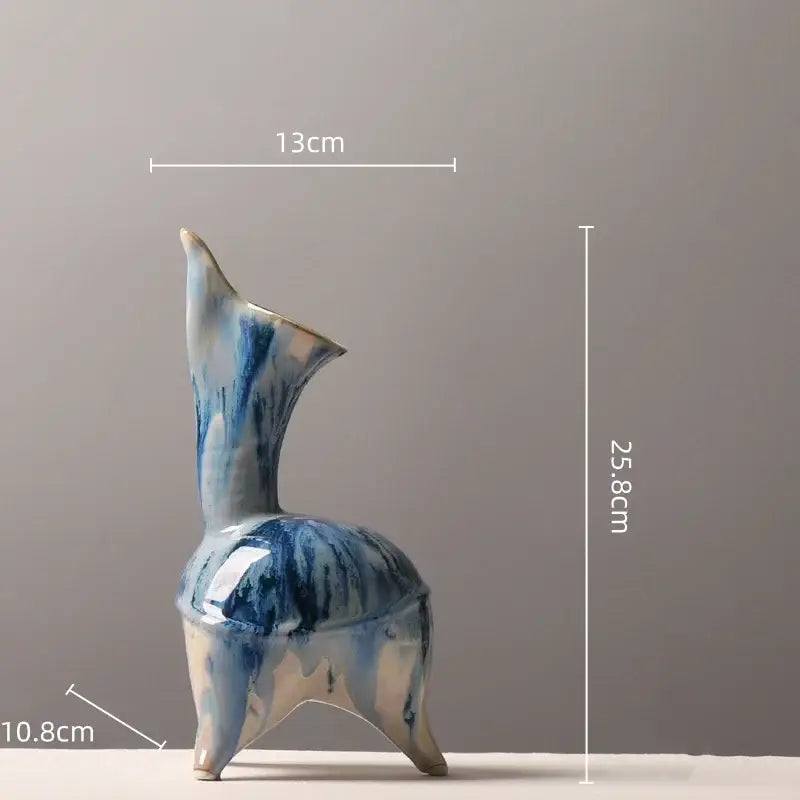 A blue and white glazed ceramic vase with irregular ink pattern, tall slender neck, and three tripod legs for living room decor