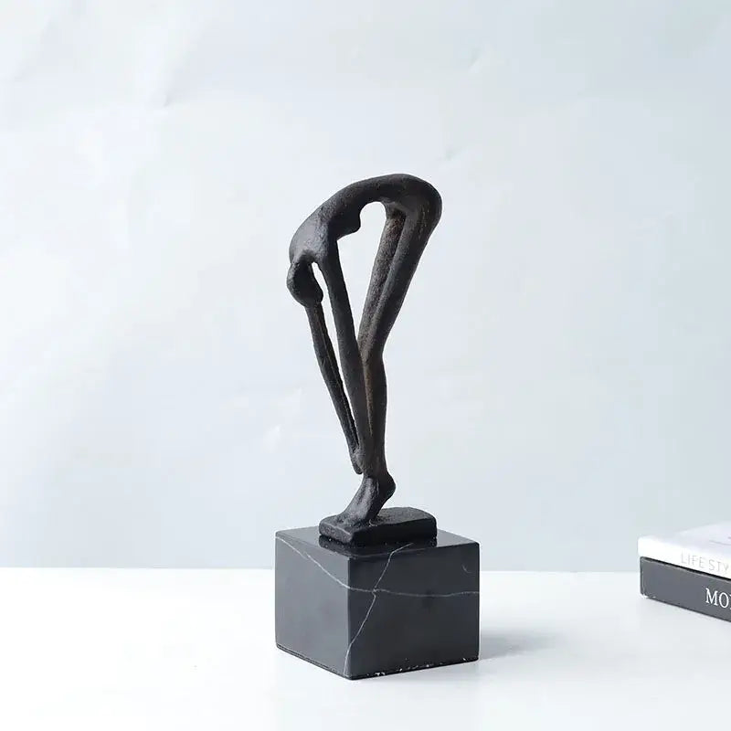 Black abstract diving sportsman metal sculpture of intertwined figures on dark marble base for living room decor