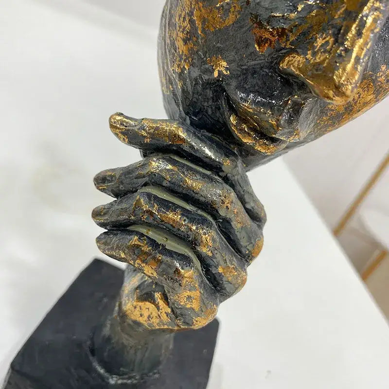 A textured black and gold abstract bronze golden mask bird figurine statue with clasped hands on a dark base for office decor