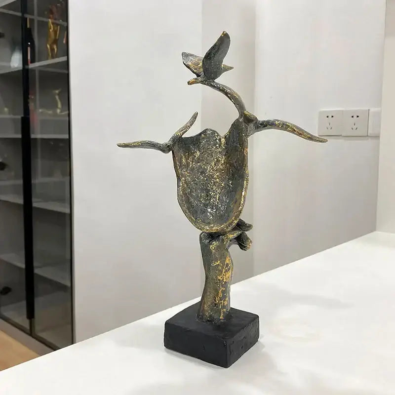 Antique bronze-colored abstract golden mask bird figurine statue with textured branch base for office decor