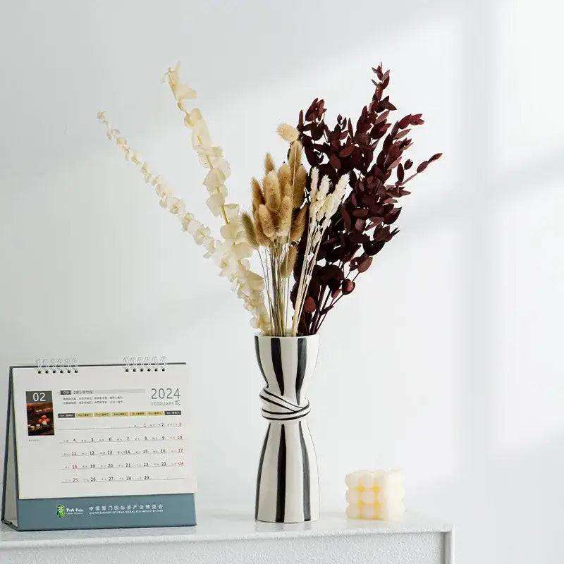 A sleek abstract ceramic hydroponic vase in black and white with bold stripes and a distinctive twisted band design