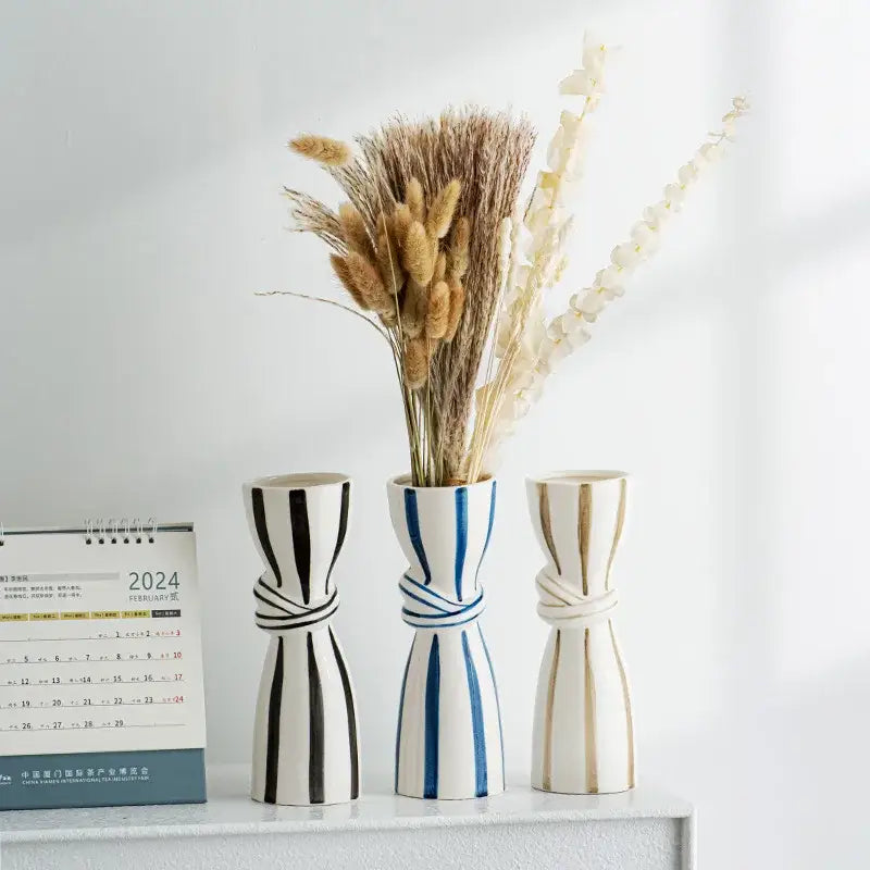 Three abstract ceramic hydroponic vases with striped knotted designs in black-and-white blue and beige tones double ear style