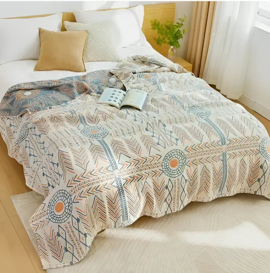 Beige quilted decorbites cotton nordic throw blanket with geometric and feather-like patterns in muted blue orange and gray tones
