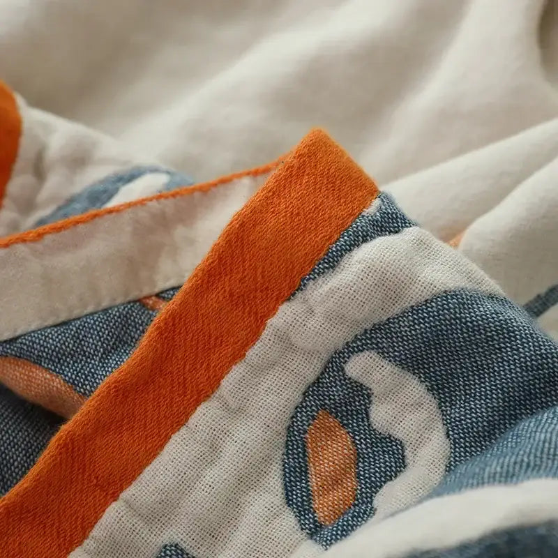 A cozy cream and blue cotton nordic throw blanket with geometric pattern and vibrant orange trim for decorbites cotton nordic decor
