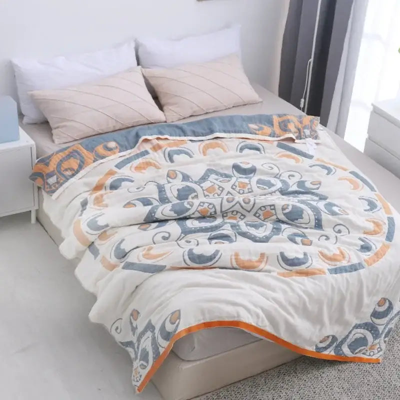A soft cream and blue cotton nordic throw blanket with quilted mandala pattern and orange-trimmed edge by decorbites cotton nordic