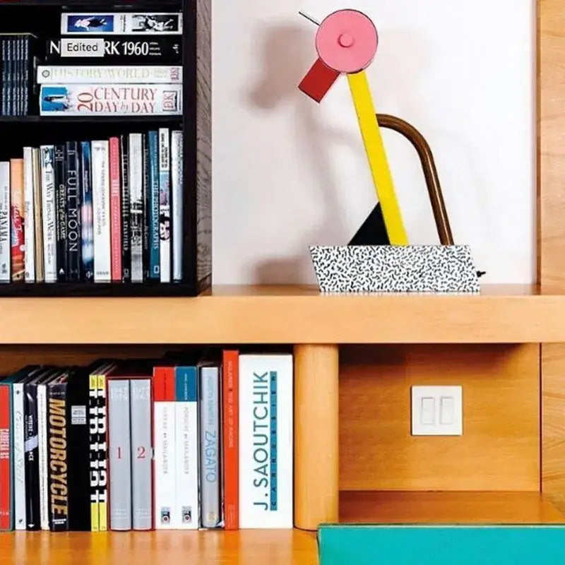 Abstract duck led table lamp with a pink circular top yellow and red angular arms and speckled black and white base