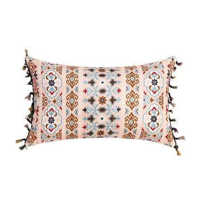 Rectangular cushion cover with soft pink base and abstract geometric patterns in coral teal with tassel decorbites accents