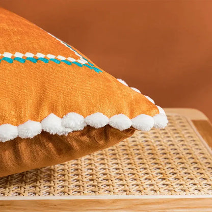 Orange cushion cover with white pom-pom trim and turquoise abstract geometric printed decorbites pattern for living room decor