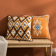 Two decorative throw pillows with orange and blue decorbites abstract geometric printed cushion cover on wooden bench