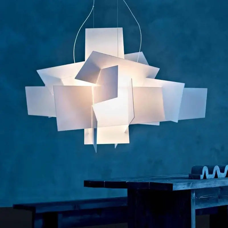 A modern white geometric pendant lamp with layered angular panels suspended by thin cords for decorbites big bang led decor