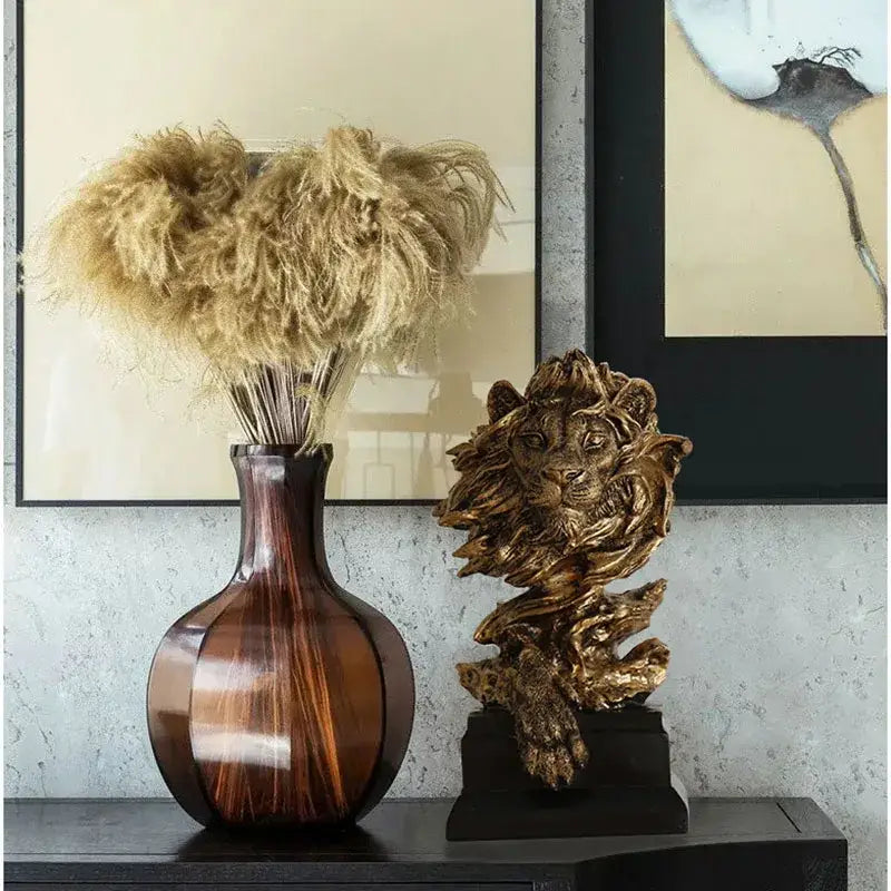 Brown glossy ceramic vase with rounded body and slender neck next to abstract gold lion resin sculpture figurine decorbites lion resin