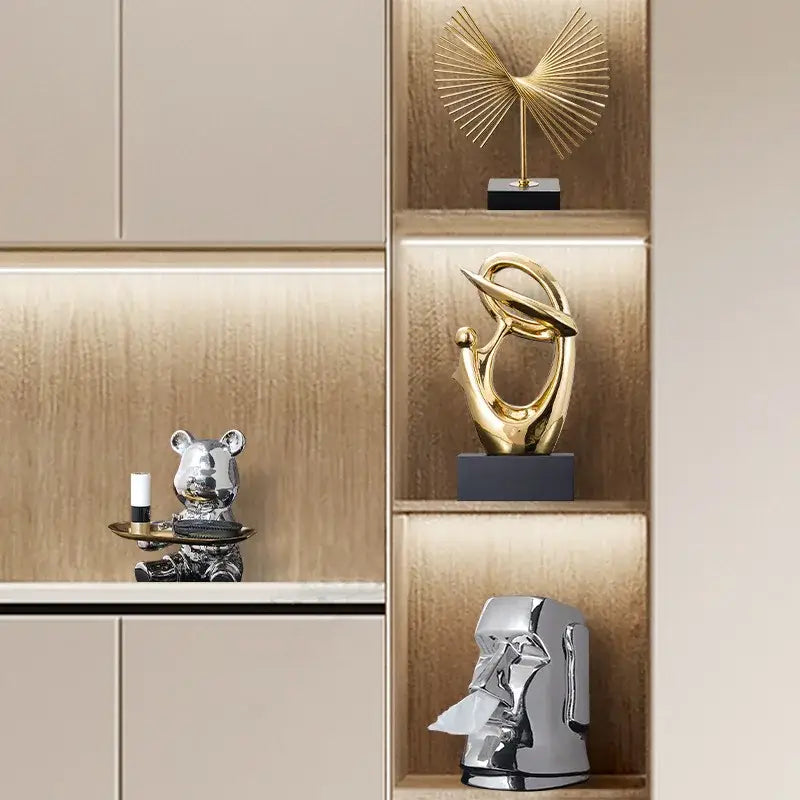 Shiny gold abstract decorative figurine with flowing golden geometric human forms on a dark gray base for living room decorbites