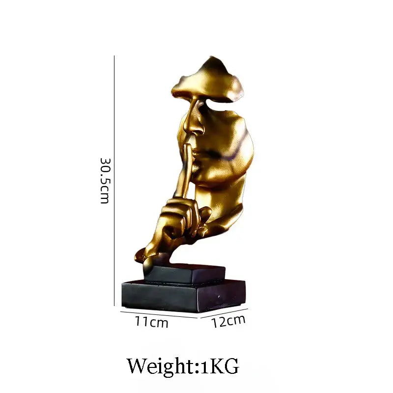 Gold resin statue of an abstract eagle face with finger pressed to lips mounted on a black rectangular base for decor