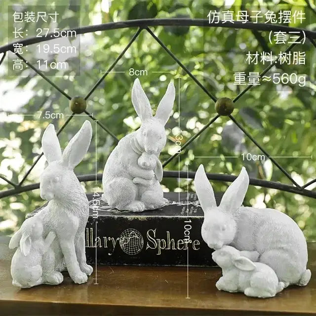 Set of three white resin figurines of mother and baby rabbits paired with an abstract gold resin statue for living room decor