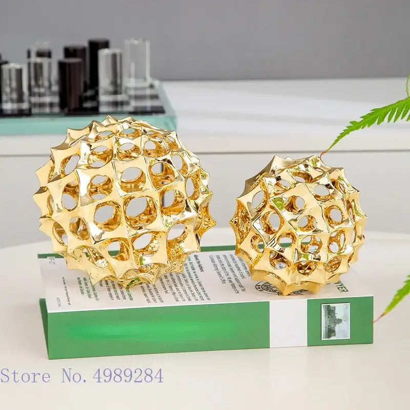 Two golden metal hollow ball spike ornaments with intricate geometric lattice design for living room decor