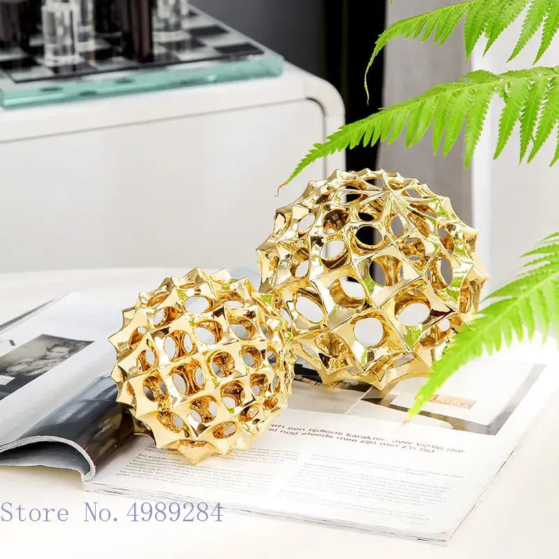 Two golden hollow ball spike ornaments with geometric metal pattern for abstract living room decor