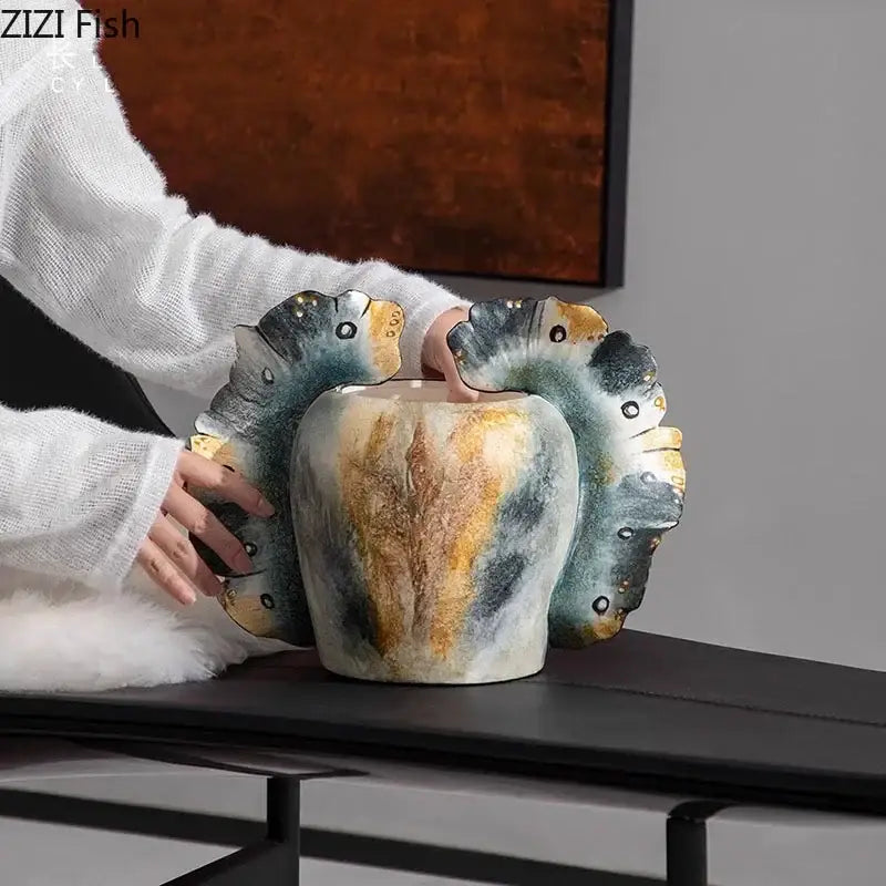 A ceramic butterfly wings vase with textured blue green and gold glaze and sculpted fish fins for bedroom decor