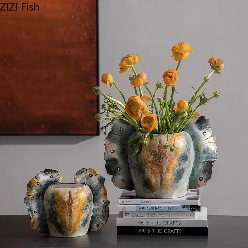 A ceramic butterfly wings vase with textured abstract fish scale and feather design in gray orange and yellow tones for bedroom decor