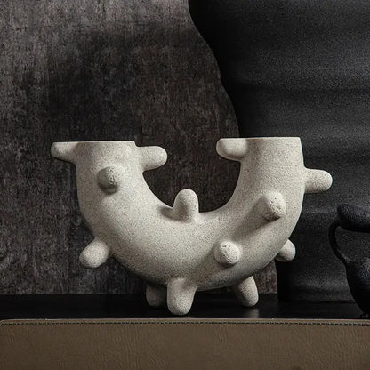 Abstract gray geometric cactus resin sculpture with gray textured ceramic vase featuring curved u-shaped form and rounded protrusions