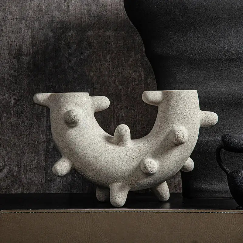 Abstract gray geometric cactus resin sculpture with gray textured ceramic vase featuring curved u-shaped form and rounded protrusions