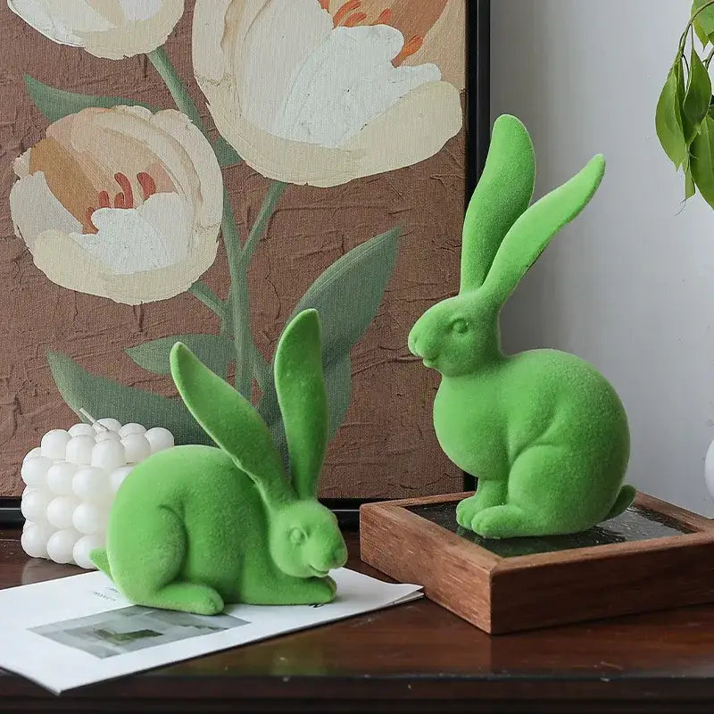 Two vibrant green plush-textured abstract rabbit figurines in seated and crouching poses made of resin decor art