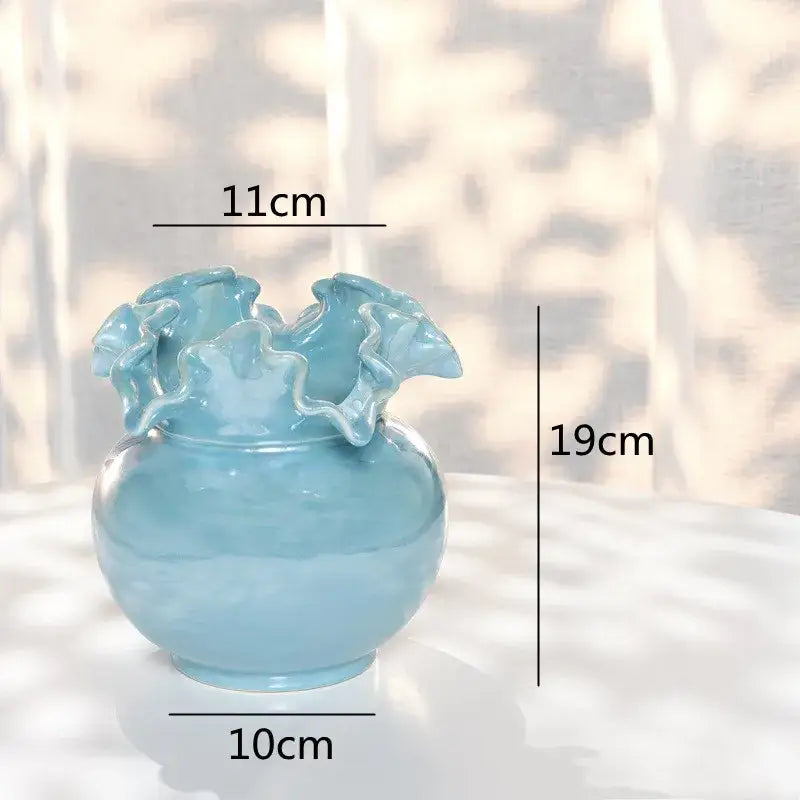 A light blue decorbites ceramic shell vase with a rounded body and ruffled rim for living room decor