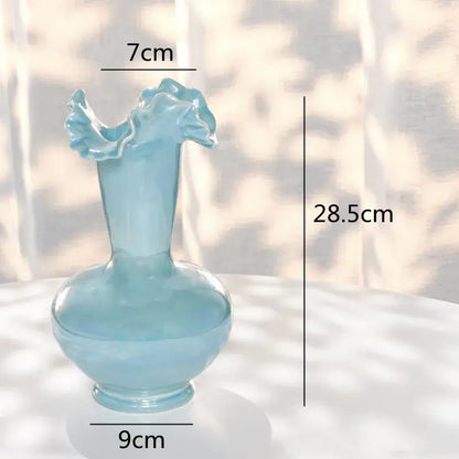 A translucent light blue glass vase with a fluted leaf rim and bulbous base for decorbites ceramic shell decor