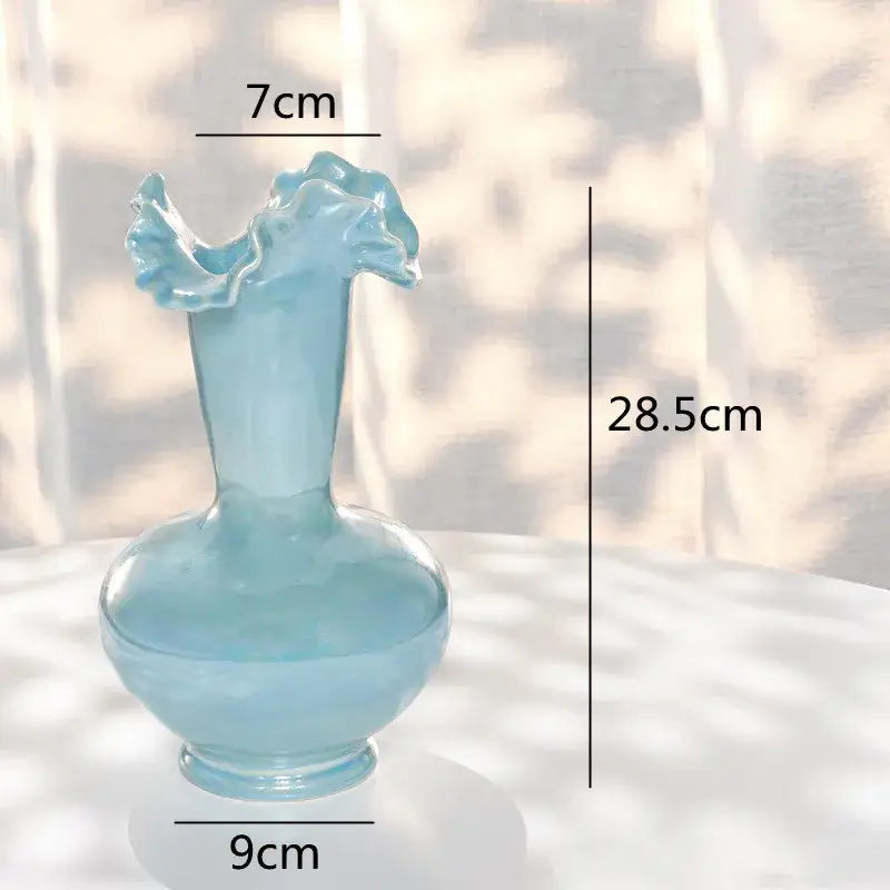 A translucent light blue glass vase with a fluted leaf rim and bulbous base for decorbites ceramic shell decor