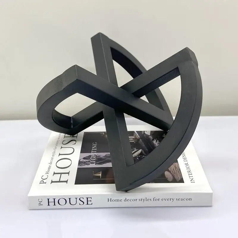 Black matte-finished geometric sculpture with interlocking curved arms as an abstract home decoration black ornament abstract