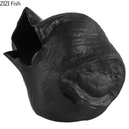 Black cast iron fish-shaped pet house with textured rustic surface and open mouth design as abstract artwork decorbites black vase