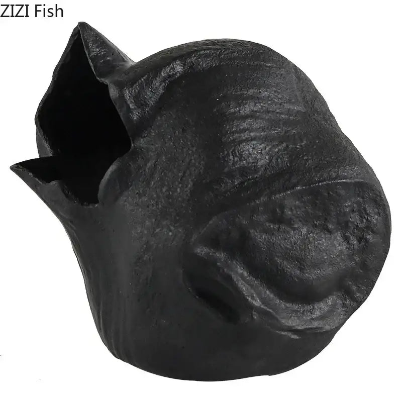 Black cast iron fish-shaped pet house with textured rustic surface and open mouth design as abstract artwork decorbites black vase