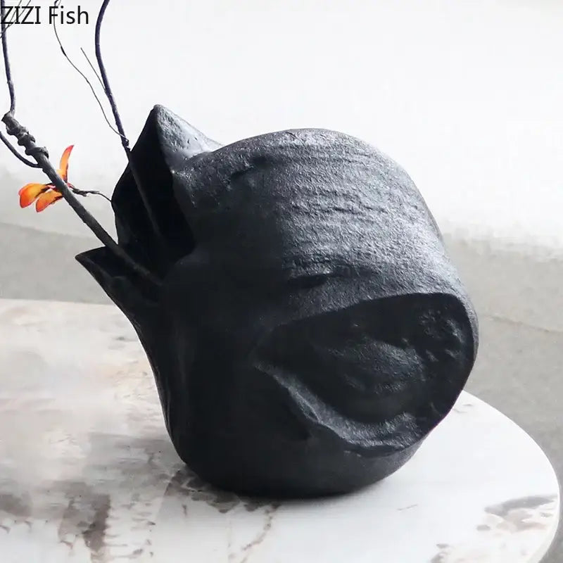 Abstract artwork black ceramic vase shaped like a stylized fish holds orange flowers for living room decorbites black vase