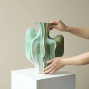 Abstract mint and olive ceramic vase with irregular folds and flowing wave like contours for living room decor