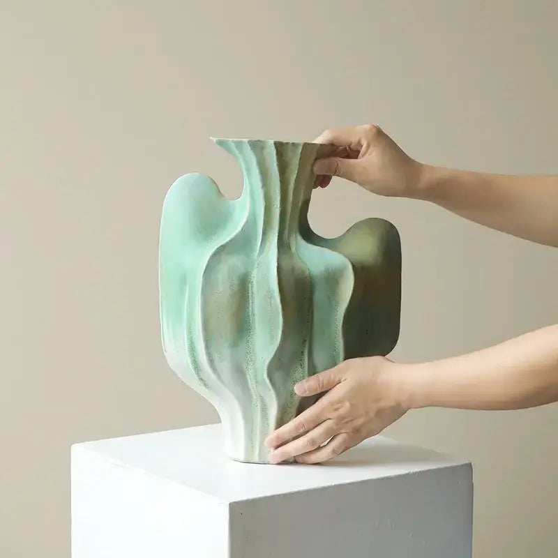 Abstract mint and olive ceramic vase with irregular folds and flowing wave like contours for living room decor